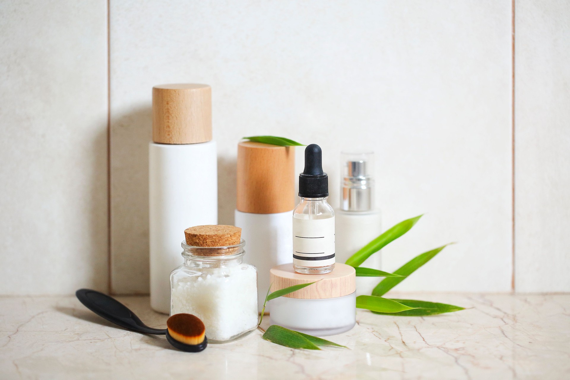 Face cream, serum, lotion, moisturizer and sea salt  among bamboo leaves