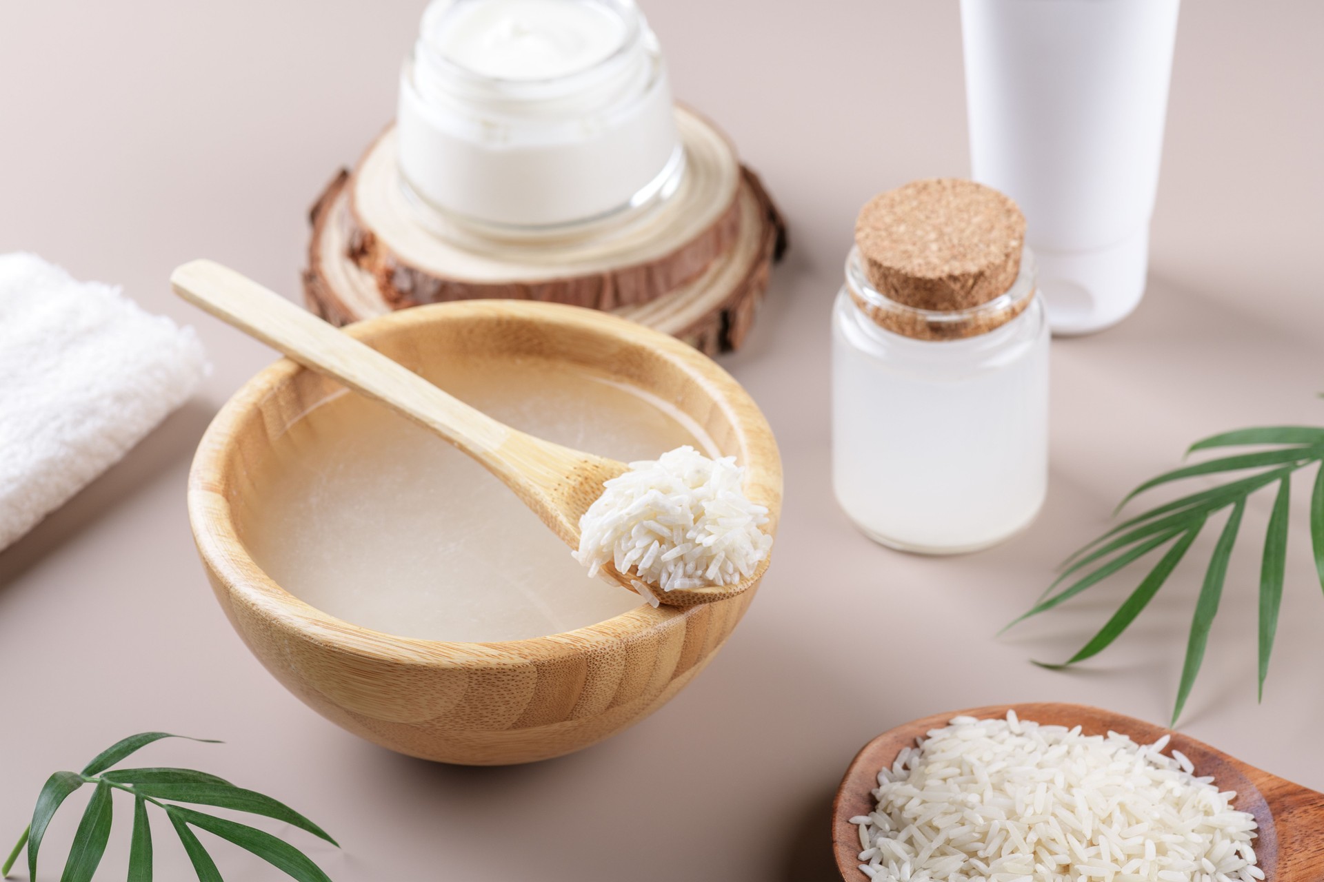 Homemade cosmetic rice water with ingredients and beauty kit on beige background